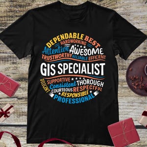 May include: Black t-shirt with the words "GIS SPECIALIST" in large white letters. The shirt features a circular design with words like "Dependable," "Awesome," and "Professional" in blue, orange, and white.