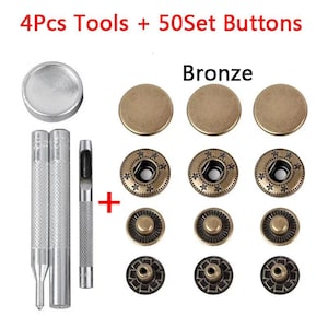 May include: A set of 4 metal installation tools and 50 bronze-colored snap buttons. The kit includes a silver circular base, two textured metal punches, and a hollow punch. The buttons feature a smooth cap and a star-patterned rim design.