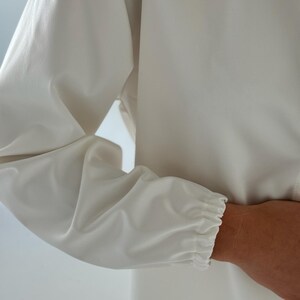 May include: A white long-sleeved shirt with a gathered elastic cuff at the wrist.