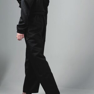 May include: A black cropped jacket and matching wide-leg trousers. The jacket has a zip fastening and a drawstring waist. The trousers have a high waist and a straight leg.