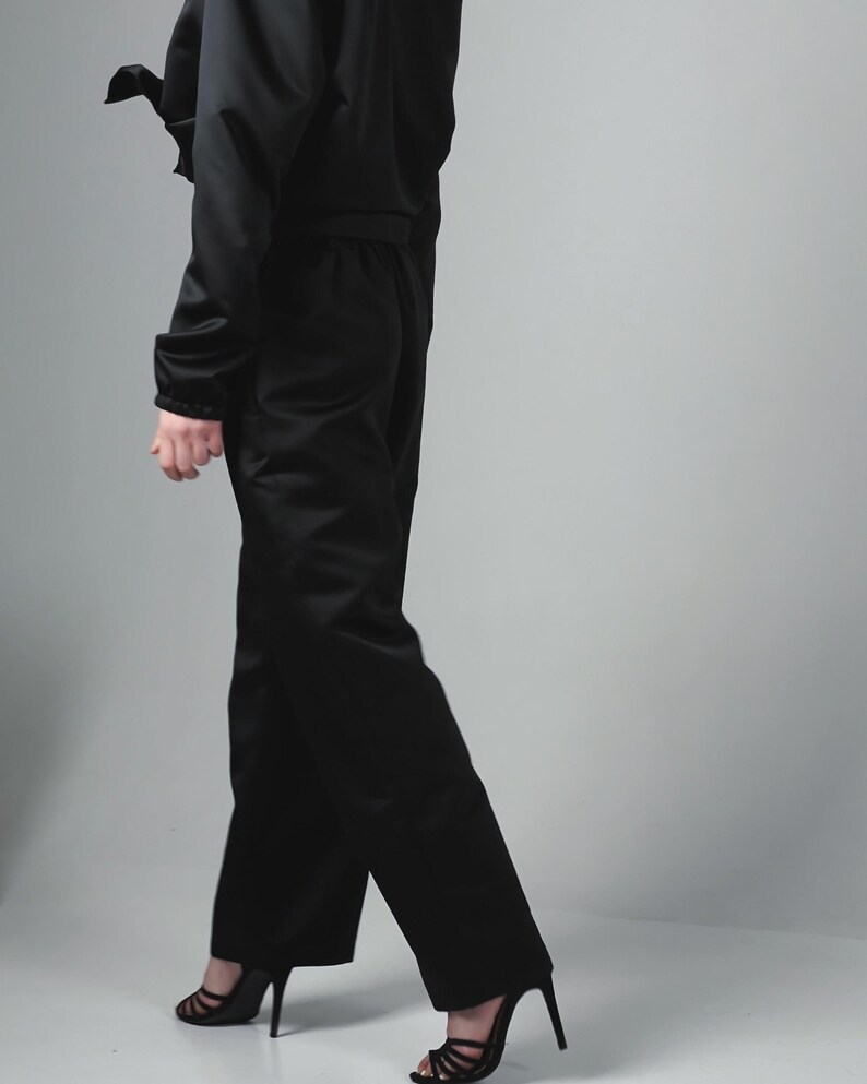 May include: A black cropped jacket and matching wide-leg trousers. The jacket has a zip fastening and a drawstring waist. The trousers have a high waist and a straight leg.