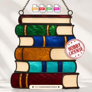 May include: A stained glass suncatcher featuring a stack of five books with textured glass in shades of red, green, blue, amber, and teal. The design includes a circular red stamp that reads HOBBY LICENSE and a label stating FREE HUMMINGBIRD BONUS.