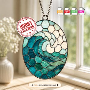 May include: An oval stained glass suncatcher featuring a wave design in shades of teal, blue, and white. The piece is suspended by a metal chain and includes a circular stamp that reads HOBBY LICENSE and a text label stating FREE HUMMINGBIRD BONUS.