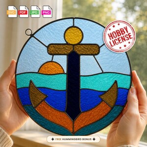 May include: A circular stained glass suncatcher featuring a dark blue anchor centered against a light blue sky, a bright orange sun, and layered waves in shades of teal and dark blue. The piece is framed in black metal with a small hanging loop.