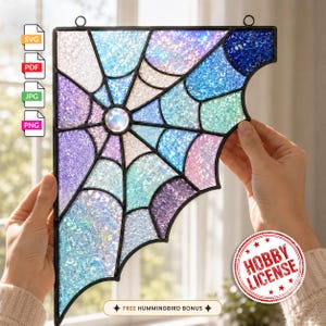 May include: A corner-shaped stained glass panel featuring a spider web design with iridescent, glittery segments in shades of blue, purple, and white. The piece is framed in black metal and includes a circular iridescent centre accent piece.
