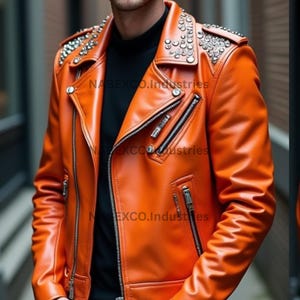 May include: Orange leather jacket with silver stud embellishments on the shoulders. The jacket has a classic biker style with a notched collar, asymmetrical zipper, and multiple zippered pockets. The text "NABEXCO.Industries" is visible on the jacket.
