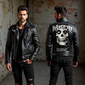 以下が含まれることがあります： 銀色のスタッズとスパイクが付いた黒い革のジャケットが2つ。1つのジャケットには、白いドクロのグラフィックと「Misfits」と「Dusna」の文字が背中にあります。