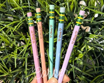 May include: Five colorful pencils with a green stripe and a heart with the name "Olivia" written on each pencil.