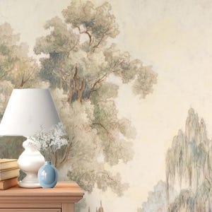 May include: A watercolor painting of a landscape with trees and a building in the background. The painting is in shades of green, brown, and white. A white lamp with a blue vase of white flowers sits on a wooden nightstand.