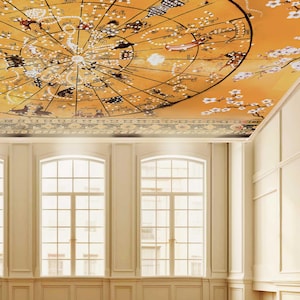 May include: A ceiling mural featuring a circular celestial map with black astrological symbols and constellations on an orange background, accented by white cherry blossom branches. The design includes intricate black line work and text.