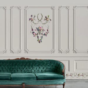 May include: A tufted emerald green velvet sofa with a wooden frame sits below a wall with white molding and a floral design. The wall features a large floral arrangement with pink, purple, and green flowers.