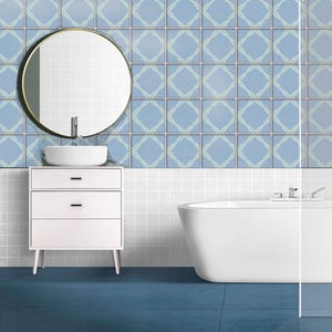 Puede incluir: Un cuarto de baño moderno con un tocador blanco, un espejo redondo y un lavabo blanco. Las paredes están adornadas con azulejos azules con un diseño de rombos y el suelo es de color azul oscuro. También hay una bañera blanca.