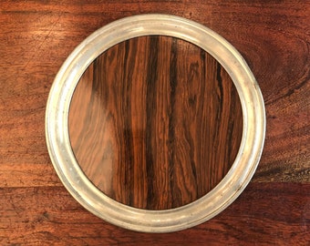 Peut inclure: Un plateau rond en bois avec un bord argenté. Le plateau a un motif de grain de bois foncé.