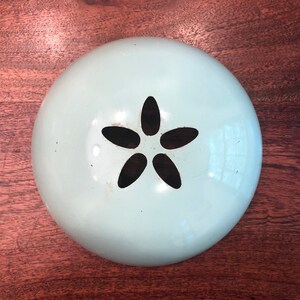 May include: A light blue metal bowl with a black five-pointed star cutout in the centre.