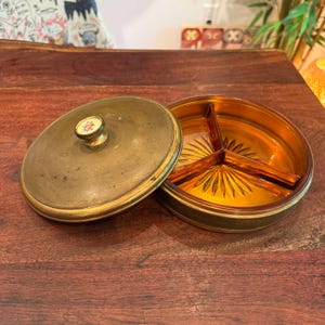 Bol para dulces/joyas antiguo de Apollo Brass de la década de 1930, con tapa dividida e inserto de vidrio ámbar, con pomo floral de porcelana - N.° 3877/7