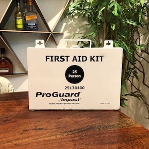 May include: White metal first aid kit with black text and a black circle that says "25 Person". The kit says "ProGuard by impact" and "Made in USA".