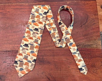 May include: A cream-coloured necktie featuring a repeating pattern of hats in shades of orange, blue, and brown. The tie is displayed on a wooden surface, highlighting its design and texture. A classic accessory.