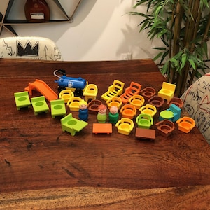 Peut inclure: Ensemble de jouets colorés comprenant des meubles et des figurines : chaises, tables, toboggan et un wagon de train bleu. Les jouets sont de couleurs variées, comme le vert, l'orange, le jaune et le marron, disposés sur une surface en bois.