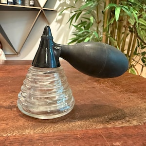 May include: A clear glass atomizer with a ribbed, beehive-shaped base and a black plastic nozzle assembly featuring a large, oval-shaped black rubber bulb. The base of the black plastic nozzle is embossed with the text DeVilbiss 121.