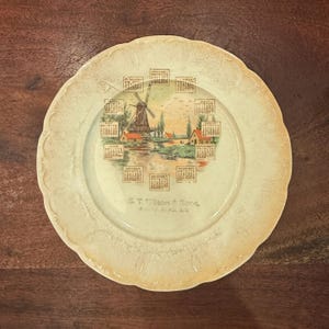 Antiquités c. 1914 S.T. Wilson & Sons Malta Bend Missouri Assiette calendrier décorative en céramique 8,5 po. avec moulin à vent hollandais et art du port