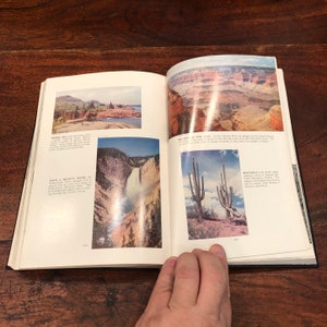 May include: An open book with two pages showing colourful images of natural landscapes. The left page shows a waterfall cascading down a rocky cliff, while the right page features a view of a canyon with a river winding through it. The text on the left page reads "With a mighty roar, the Yellowstone River plunges 308 feet deep..."
