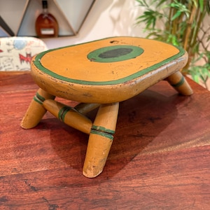 Taburete/reposapiés antiguo de madera de pino, pintado a mano, de estilo folclórico americano, en verde calabaza y negro.