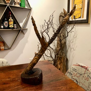 May include: A wooden sculpture of a tree branch with intricate carvings. The sculpture is mounted on a wooden base and has a natural brown color.