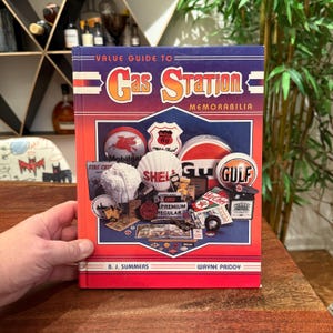 Puede incluir: Un libro titulado "Value Guide to Gas Station Memorabilia". La portada roja, azul y naranja presenta logotipos y recuerdos de gasolineras vintage. Los autores son B.J. Summers y Wayne Priddy.