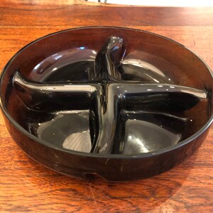 May include: A dark brown glass divided dish with four sections. The dish is round and has a smooth, glossy finish.