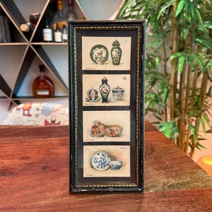 May include: A framed print featuring four panels of antique china illustrations. The panels showcase various teacups, saucers, bowls, and decorative jars in detailed drawings. The frame is black with a textured, ornate design, adding a vintage aesthetic.