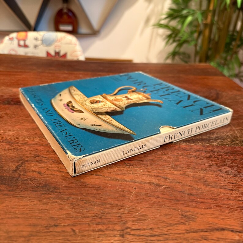 May include: A vintage book titled "French Porcelain Treasures and Treasures" with a blue cover and an illustration of a porcelain object. The book is by Landais and published by Putnam.