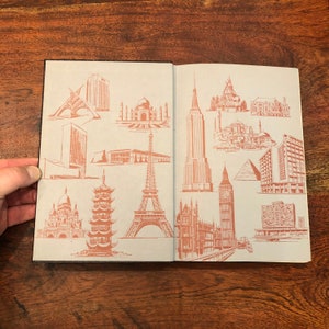 May include: An open book featuring illustrations of famous landmarks from around the world. The illustrations are in red ink on a light blue background. The landmarks include the Eiffel Tower, the Taj Mahal, the Empire State Building, and the Houses of Parliament.
