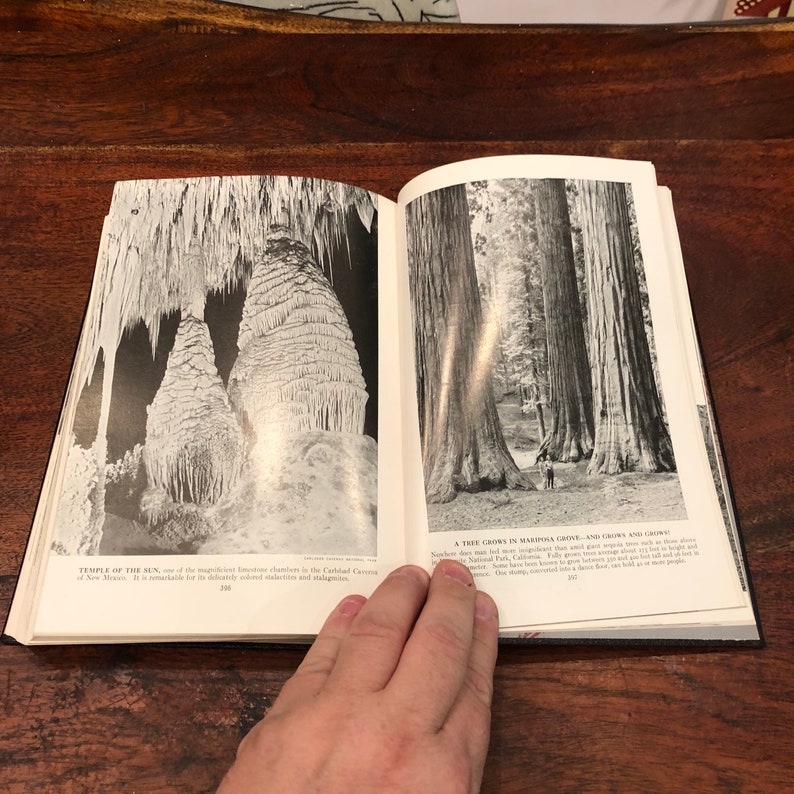 May include: A black and white photograph of a book open to two pages. The left page shows a photo of a cave with large rock formations. The right page shows a photo of a grove of tall trees. The text on the left page reads "Temple of the Sun, one of the magnificent limestone chambers in the Carlsbad Caverns of New Mexico. It is remarkable for its delicately-shaped stalactites and stalagmites." The text on the right page reads "A Tree Grows in Mariposa Grove - and Grows and Grows. Nowhere does man find a sight more magnificent than that giant sequoia grove, each tree in which is older than the oldest civilization. Fully grown trees average 100 feet in height and 25 feet in diameter. Some have been measured 300 feet in height, and one has been found to be 40 feet in diameter. One tree has been hollowed out to a dance floor, big enough for 50 people to dance in."