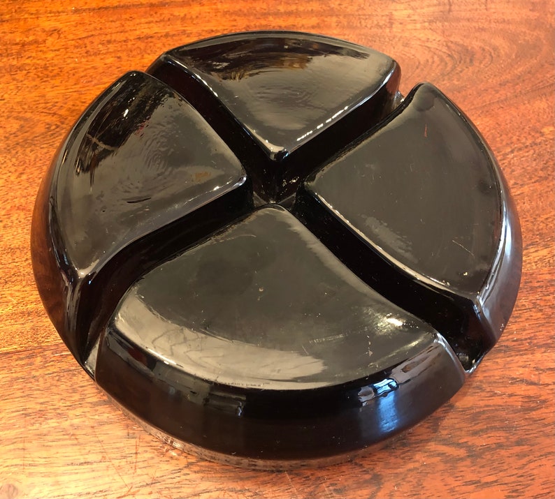 May include: A black glass divided dish with four sections. The dish is round and has a glossy finish.