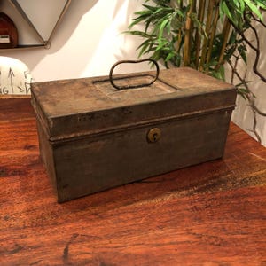 May include: A vintage metal box with a rusty finish and a metal handle. The box has a keyhole and a lock.