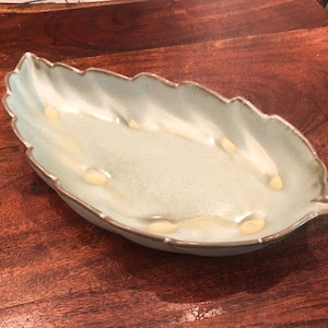 May include: A light green ceramic leaf-shaped serving dish with a textured surface.