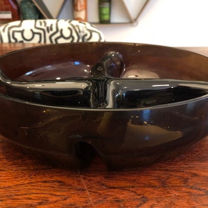 May include: A dark brown glass divided serving bowl with four sections. The bowl is round and has a slightly raised rim.