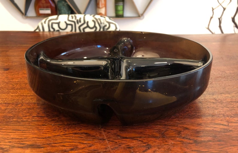 May include: A dark brown glass divided serving bowl with four sections. The bowl is round and has a slightly raised rim.