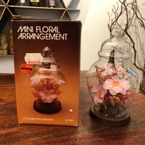 Diorama vintage de mariposas reales kitsch sobre flores artificiales, c. 1983, en campana de vidrio sobre soporte con caja, de Action Industries - Decoración kitsch de los años 80