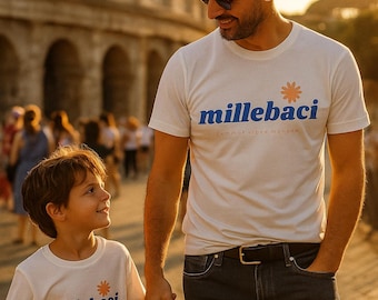 May include: A man and a child wearing matching white t-shirts with the text "millebaci" in blue and an orange flower graphic. They are holding hands and walking on a cobblestone street. The man is wearing sunglasses and dark jeans.