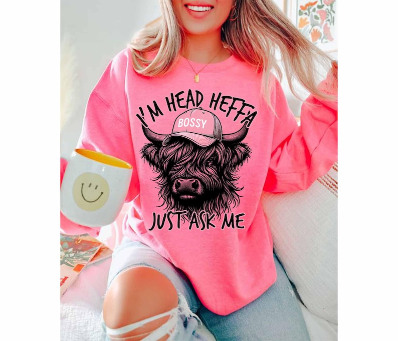 May include: A pink sweatshirt with a black highland cow wearing a hat that says "Bossy" and the text "I'm Head Heffa Just Ask Me".