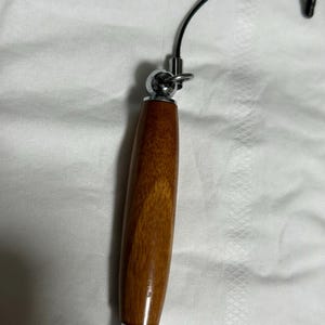 May include: A wooden stylus with a silver tip and a silver loop at the top. The stylus is attached to a black string.