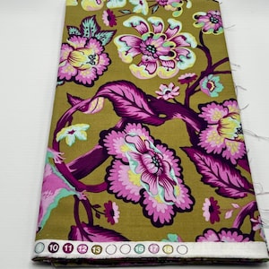 May include: A fabric with a floral pattern. The fabric is a mustard yellow color with pink, purple, and green flowers. The flowers are stylized and have a vintage look. The fabric is folded and has a white border with numbers on it.