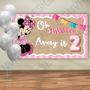 May include: A pink and brown banner with Minnie Mouse, white balloons, and the text "Oh TWOdles Avery is 2." The banner has a pink striped border and a brown center with white text. A cluster of white balloons is on the left.