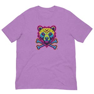 May include: A lilac-colored t-shirt featuring a colorful bear head design with crossed bones. The bear graphic has a vibrant color scheme of yellow, blue, pink, and orange. The t-shirt is made of a soft material.