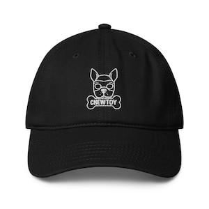 May include: Black baseball cap with a white embroidered design of a dog's face wearing goggles and a bone-shaped tag that reads "CHEW TOY". The cap has a curved brim and an adjustable strap.