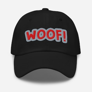 May include: Black baseball cap with the embroidered word "WOOF!" in red letters with a light gray outline. The hat has a curved brim and a fabric strap closure on the back.