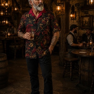 May include: A short-sleeved button-down shirt featuring a dark black background with a detailed print of red birds and golden-brown foliage. The shirt has a solid red collar and is paired with plain black trousers and dark brown leather shoes.