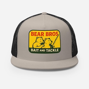 Könnte beinhalten: Beige-schwarze Trucker-Cap mit einem rechteckigen Aufnäher. Der Aufnäher zeigt den Text "BEAR BROS" über "BAIT AND TACKLE". Der Aufnäher hat einen gelben Hintergrund mit zwei Cartoon-Bären und einer Angelrute.