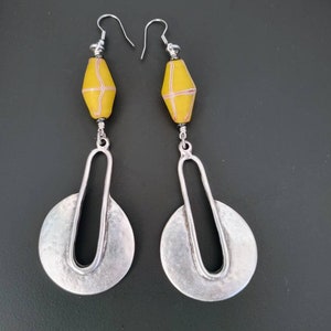 May include: A pair of silver dangle earrings with a yellow and white striped bead on each earring.